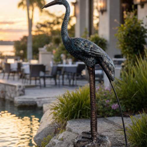Sculpture Shops heron cast aluminum garden statue displayed beside a waterfront patio