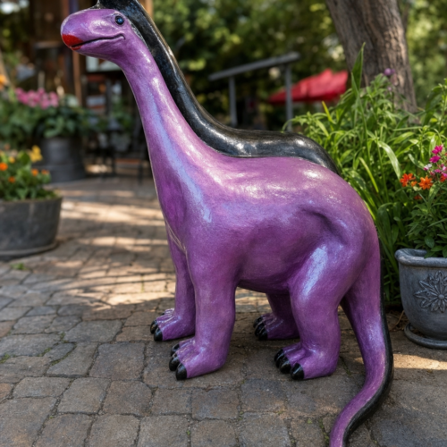 Sculpture Shops medium dinosaur cast aluminum garden statue on a patio with blurred landscaping
